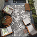 An outdoor patio setup features Couristan Dolce Indoor/Outdoor Rug - Flora/Snow centered among wooden lounge chairs and potted plants