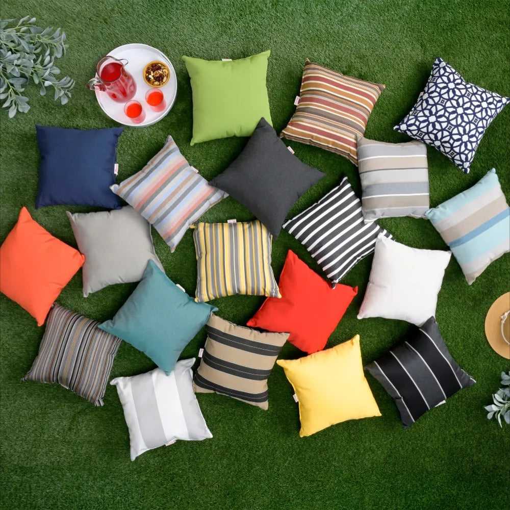 An assortment of colorful LuxCraft 19 Throw Pillows in various solid and striped patterns is spread across a grassy lawn