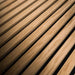 Angled close-up of GIK Acoustics SlatFusor™ Polycylindrical Diffuser emphasizing the depth, texture, and spacing of the wooden slats over a dark backing