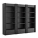 Angled view of Crate & Barrel Siena 102" Black Wood 4-Shelf Storage Bookcase with Drawer, Set of 3 featuring black wood construction fluted details and three storage drawers