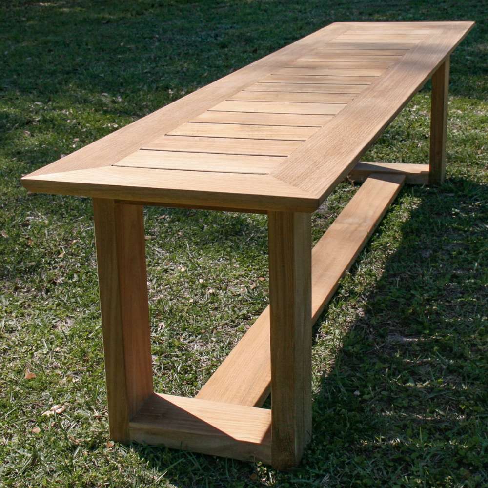Angled view of Westminster Teak 6ft Horizon Teak Backless Bench highlights its smooth teak surface and long, simple design set on grass outdoors