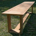 Angled view of Westminster Teak 6ft Horizon Teak Backless Bench highlights its smooth teak surface and long, simple design set on grass outdoors