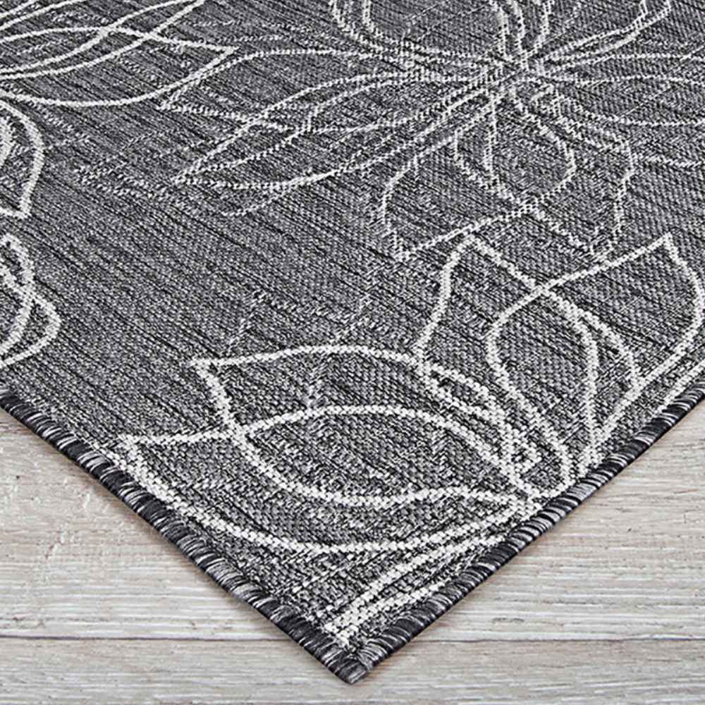 Angle of the Couristan Charm Indoor/Outdoor Rug - Botanical/Ash reveals clean edges and an elegant ash-and-white flower pattern on light wood floors