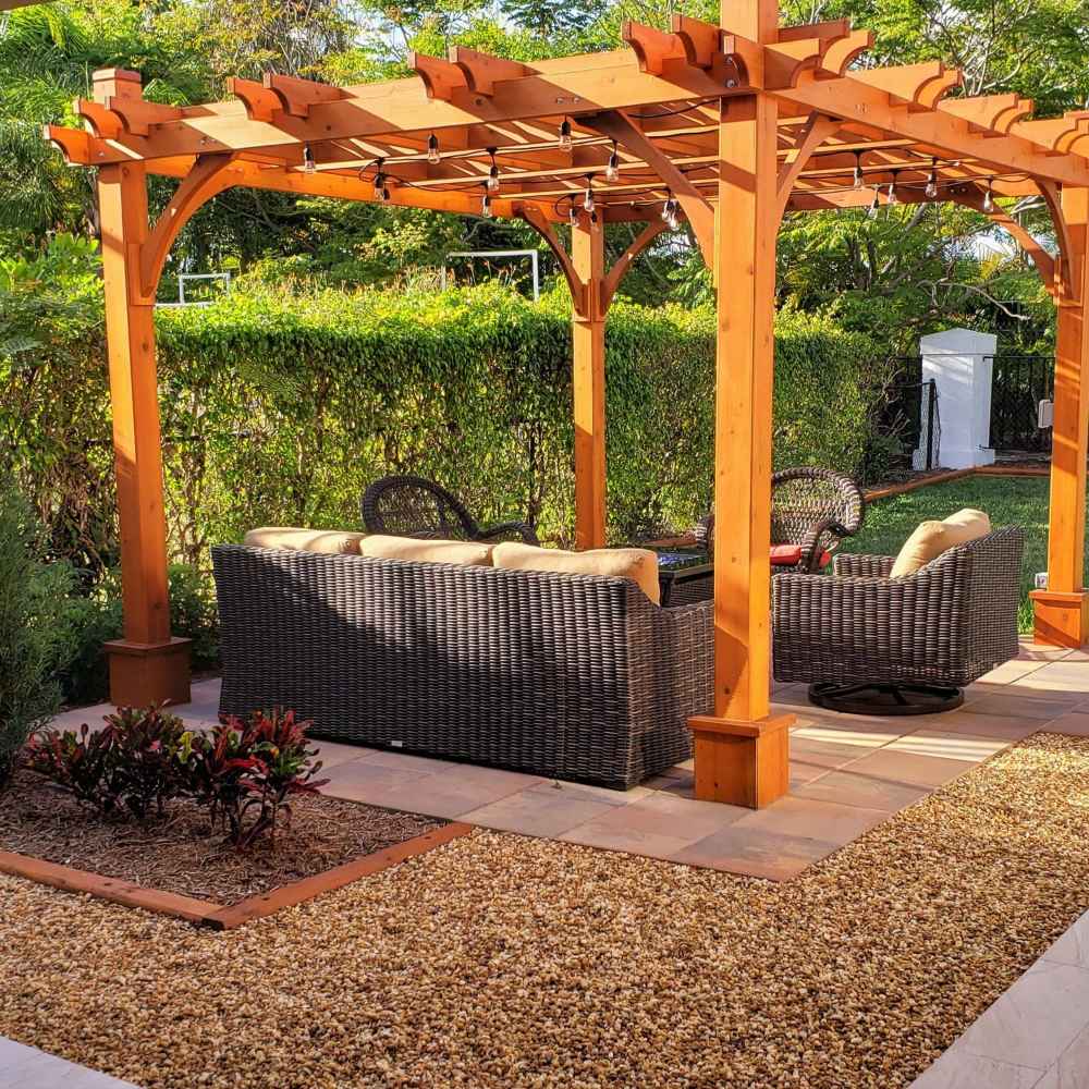 An image of the Outdoor Living Today Western Red Cedar Pergola & Canopy in a garden, showcasing outdoor wicker furniture beneath it