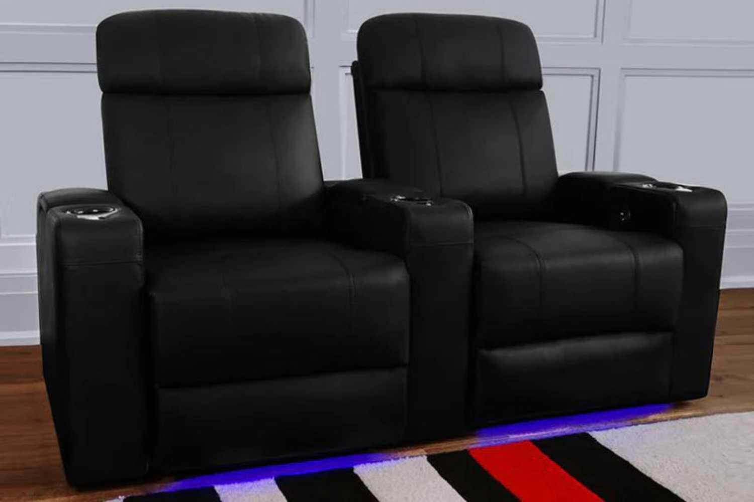 A pair of Valencia Piacenza Single Power Headrest Home Theater Seating chairs are displayed in a cozy home setting with ambient lighting