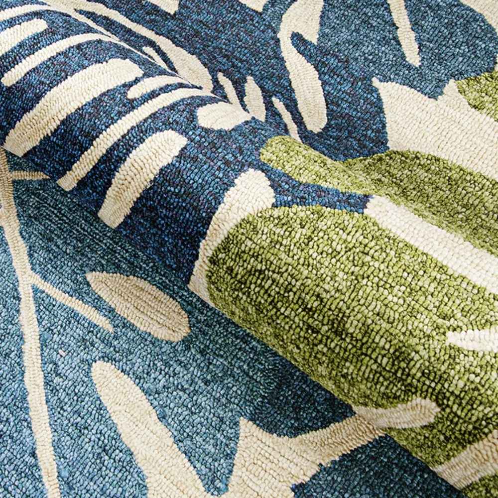 A partial fold in the Couristan Covington Indoor/Outdoor Rug - Monstera/Cream-Multi reveals its plush thickness and vibrant leaf design