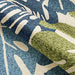 A partial fold in the Couristan Covington Indoor/Outdoor Rug - Monstera/Cream-Multi reveals its plush thickness and vibrant leaf design