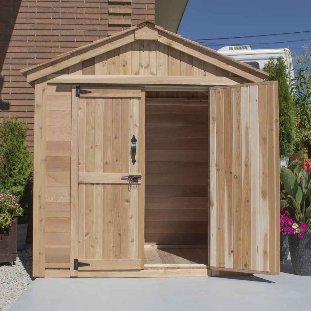 A partially opened Outdoor Living Today SpaceMaster 6×4 with Double Door shows one door open, revealing an empty wooden interior with sunlight casting inside