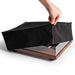 A person lifts the Crosley Fabric Turntable Dust Cover - Black to reveal a wooden turntable underneath