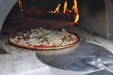 A pizza is being pulled from a blazing oven using the Chicago Brick Oven Aluminum Pizza Peel - Turning Pizza Paddle, with flames in the background