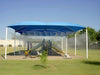 A playground under a large blue canopy is cooled by the Aeromist Pinnacle 1000 PSI Misting System releasing mist above the play structure