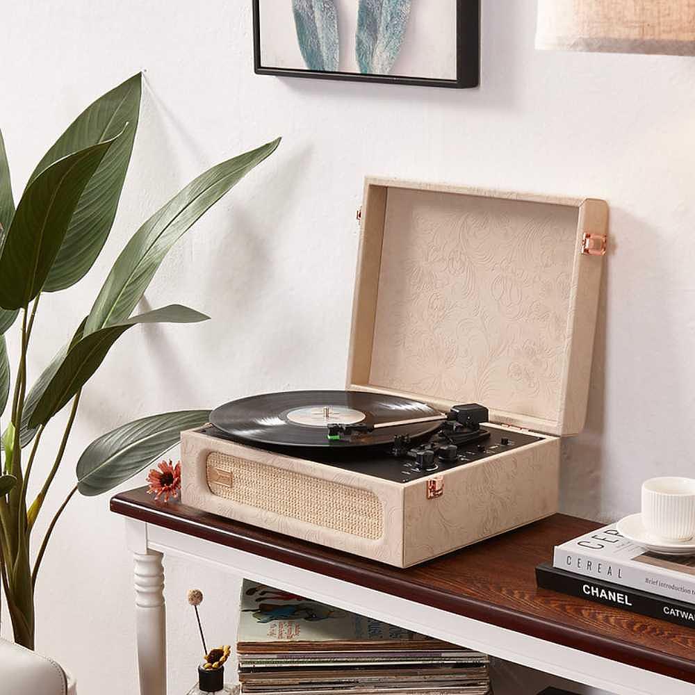 Arkrocket Coryphaeus Bluetooth Turntable Deluxe Edition Record Player (Flora Engraved) sits open on a side table next to a plant