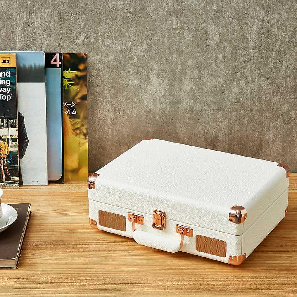 Arkrocket Curiosity Suitcase Bluetooth Turntable (Cream Rose Gold) closed and packed like a suitcase, sitting on a table with vinyl records nearby