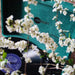 Arkrocket Curiosity Suitcase Bluetooth Turntable (Green Velvet) open with a record spinning, decorated with white flowers in the foreground