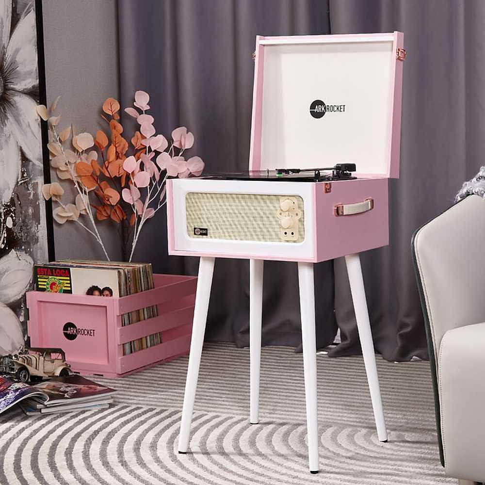 Arkrocket Discovery Bluetooth Record Player Stand with 3-Speed Turntable (PinkWhite) is set up in a cozy living room surrounded by decor and vinyl records