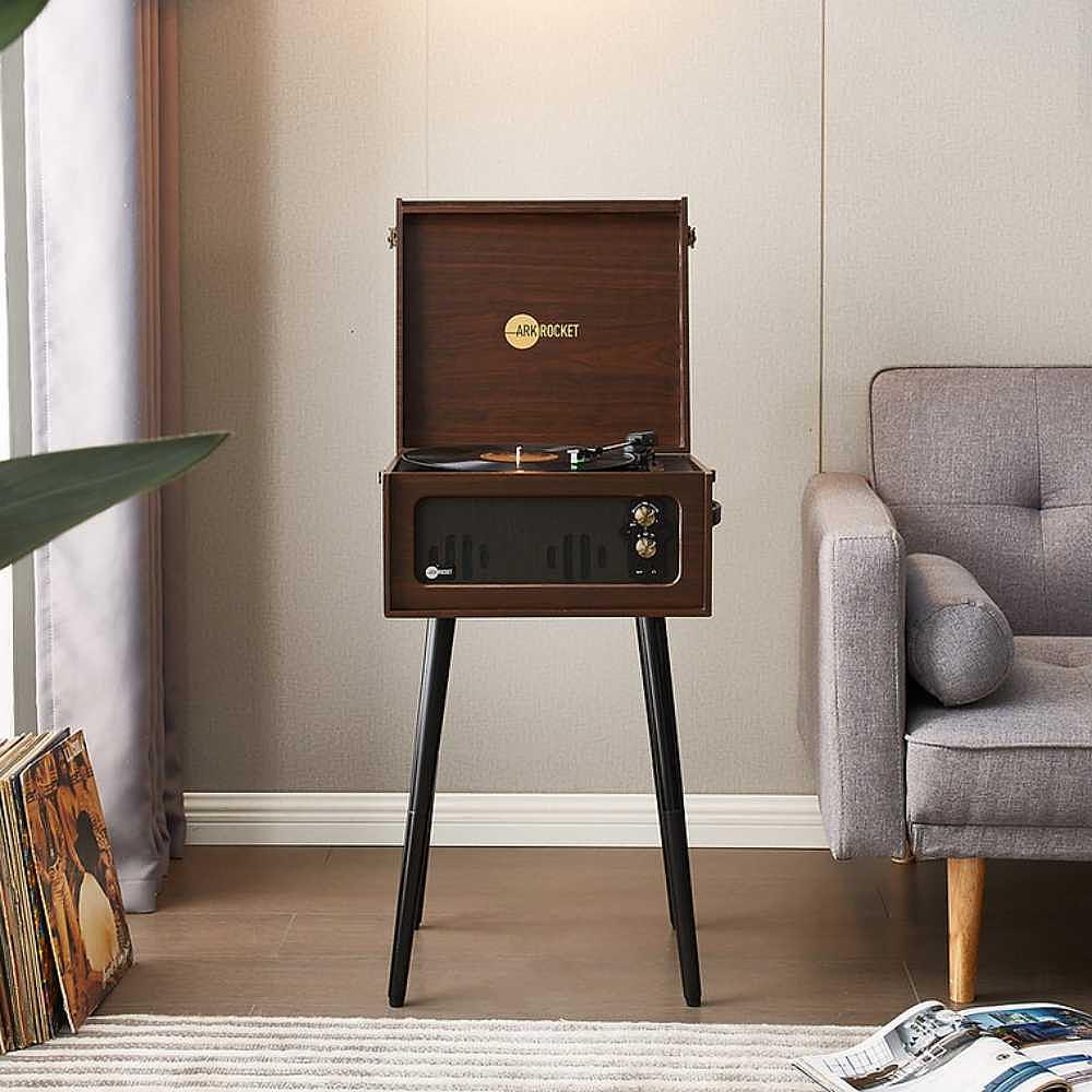 Arkrocket Discovery II Bluetooth Record Player Stand with 3-Speed Turntable (Espresso) against a light-colored wall beside a grey couch and vinyl collection