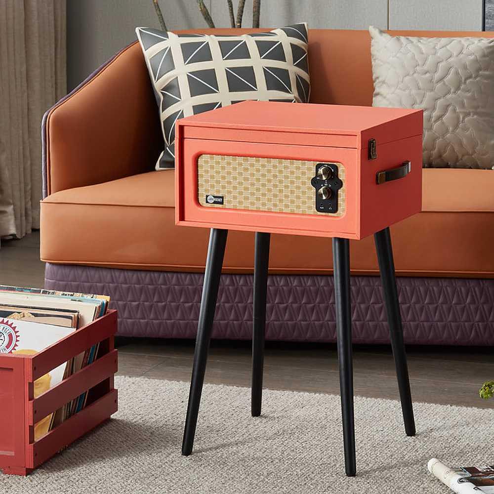 Arkrocket Discovery II Bluetooth Turntable Record Player With Legs (Orange) is placed next to an orange couch