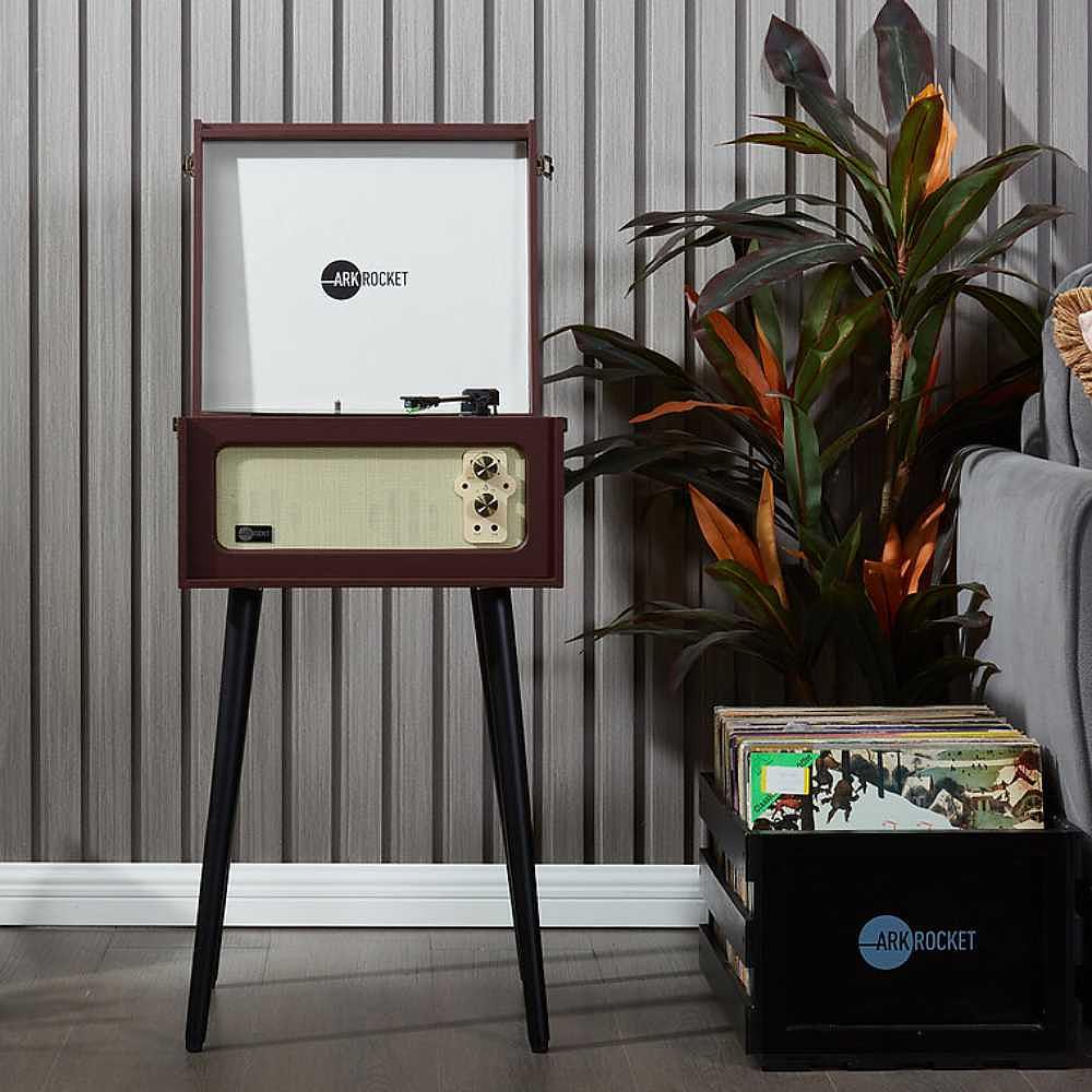 Arkrocket Discovery II Console 3-Speed Bluetooth Record Player with Legs (Brown) stands with its lid open next to a box of vinyl records