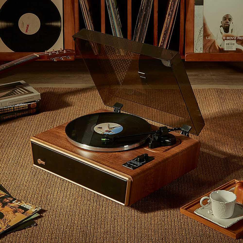 Arkrocket Huygens Bluetooth Turntable with Built-in Speakers (Walnut) on a carpeted floor surrounded by vinyl records and a tea set