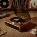 Arkrocket Huygens Bluetooth Turntable with Built-in Speakers (Walnut) on a carpeted floor surrounded by vinyl records and a tea set