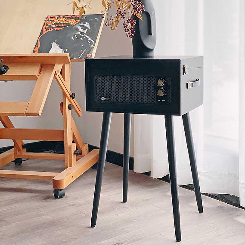 Arkrocket Retro Turntable Wireless Record Player With Legs (Black) in a room setup next to a drafting table and decorated with a vinyl record