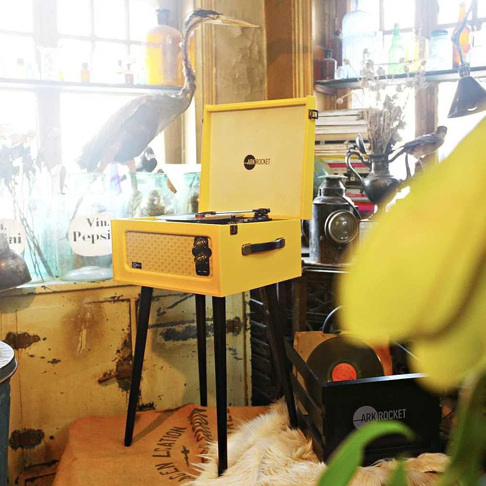 Arkrocket Retro Turntable Wireless Record Player With Legs (Yellow) is placed in a cozy vintage setting