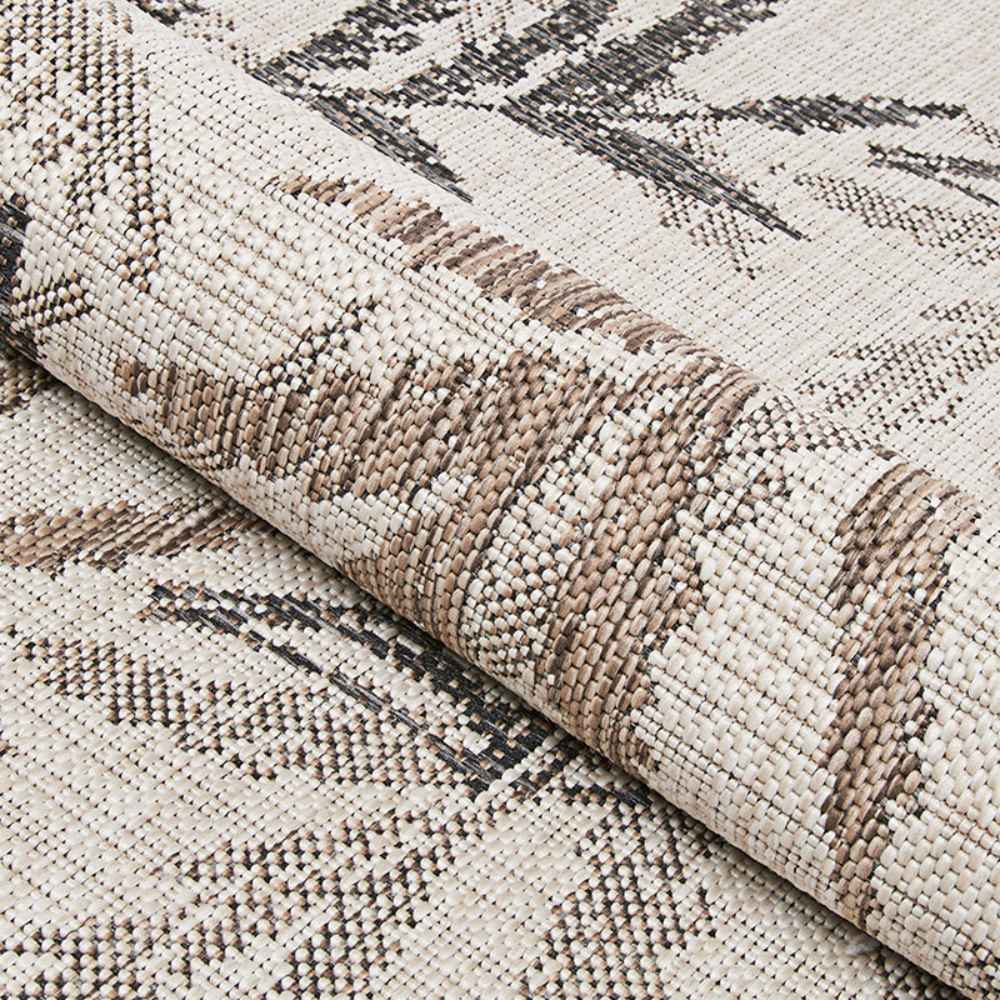 A rolled edge of the Couristan Charm Indoor/Outdoor Rug - Kimberly/Naturals displays the thick, woven texture and detailed leaf pattern