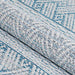 A rolled section of the Couristan Cape Indoor/Outdoor Rug - Gables/Surf highlights its thick texture and intricate diamond and zigzag patterns in surf blue and ivory