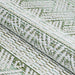 A rolled view of the Couristan Cape Indoor/Outdoor Rug - Gables/Palm highlights its thick texture and detailed geometric pattern in green and ivory tones