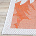 A sharp corner view of Couristan Monaco Indoor/Outdoor Rug - Coastal Flora/Ivory-Orange reveals its ivory edging and bold orange woven leaf details