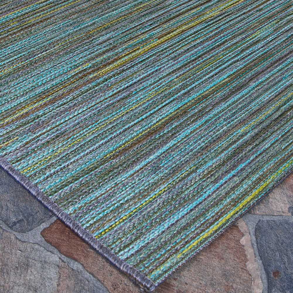 A side-angle view of the Couristan Cape Indoor/Outdoor Rug - Hinsdale/Teal-Cobalt captures its smooth texture and subtle sheen over natural stone flooring