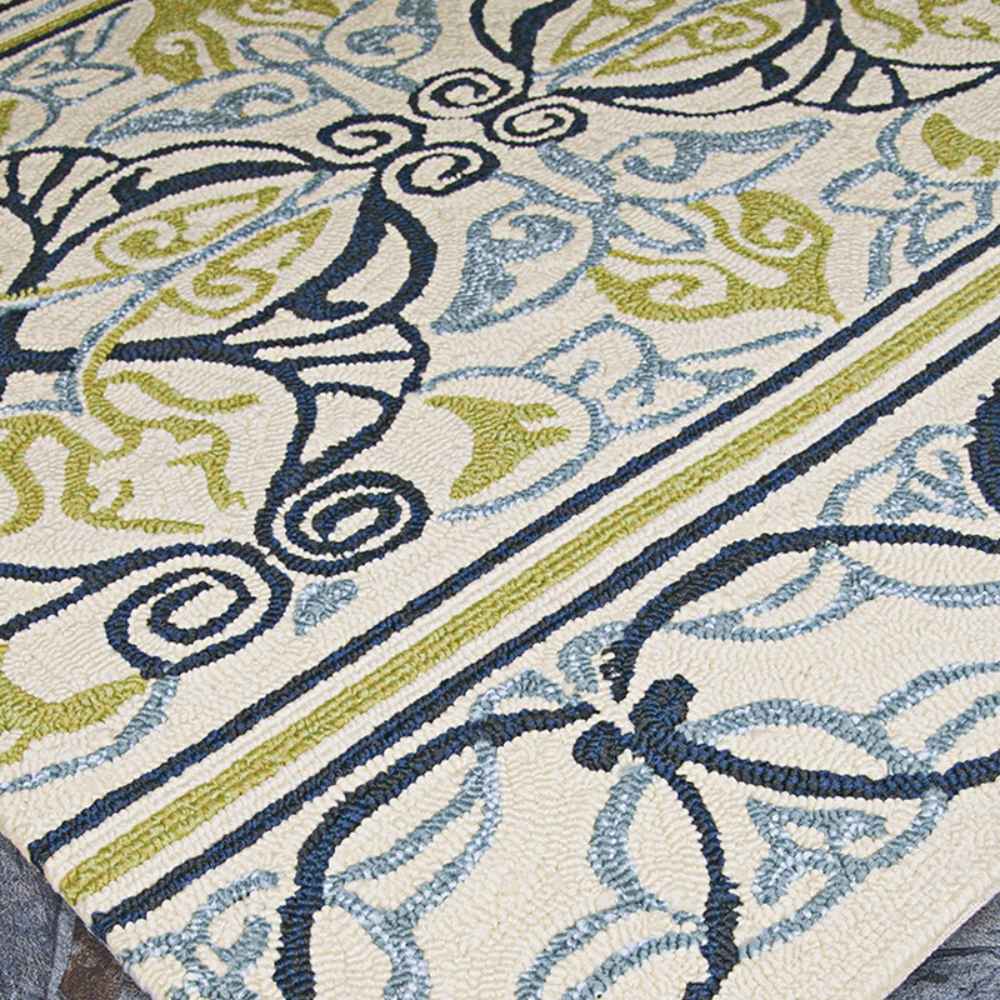 A side angle captures the intricate blue and green motifs of the Couristan Covington Indoor/Outdoor Rug - Pegasus/Ivory-Navy-Lime on a light ivory base