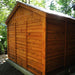A side angle view of the Outdoor Living Today 12×12 Double Door Space Master Storage Shed shows its beautifully crafted cedar wood panels under a sloped black roof