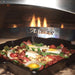 A sizzling breakfast of eggs, potatoes, and greens cooks in a cast-iron pan inside the Alfresco Grills 30 Pizza Oven Plus - Built-In