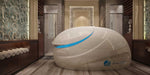 A sleek, futuristic Dreampod V2 Float Pod with a white, glossy shell and a vibrant blue accent glows in a luxurious, spa-like room