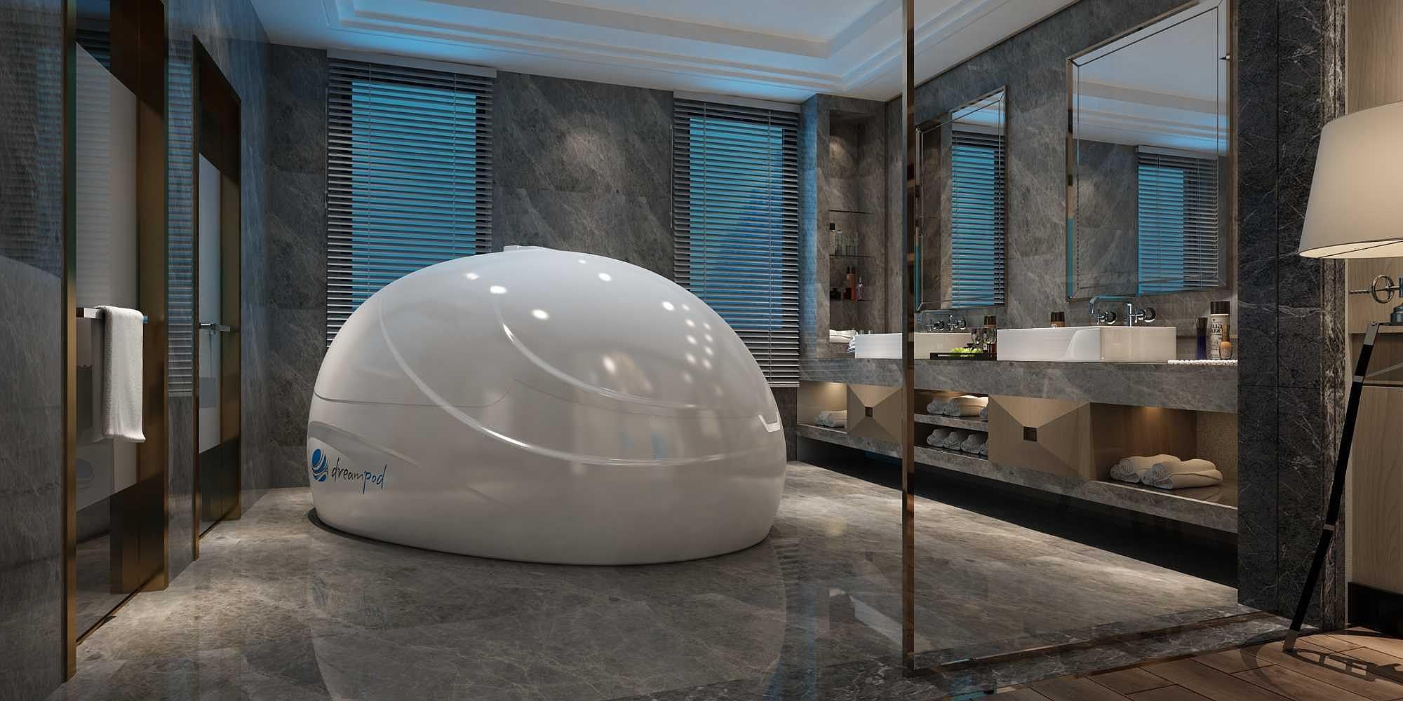 A sleek, white, egg-shaped Dreampod Sport Float Pod sits in a luxurious marble bathroom with double sinks and modern decor