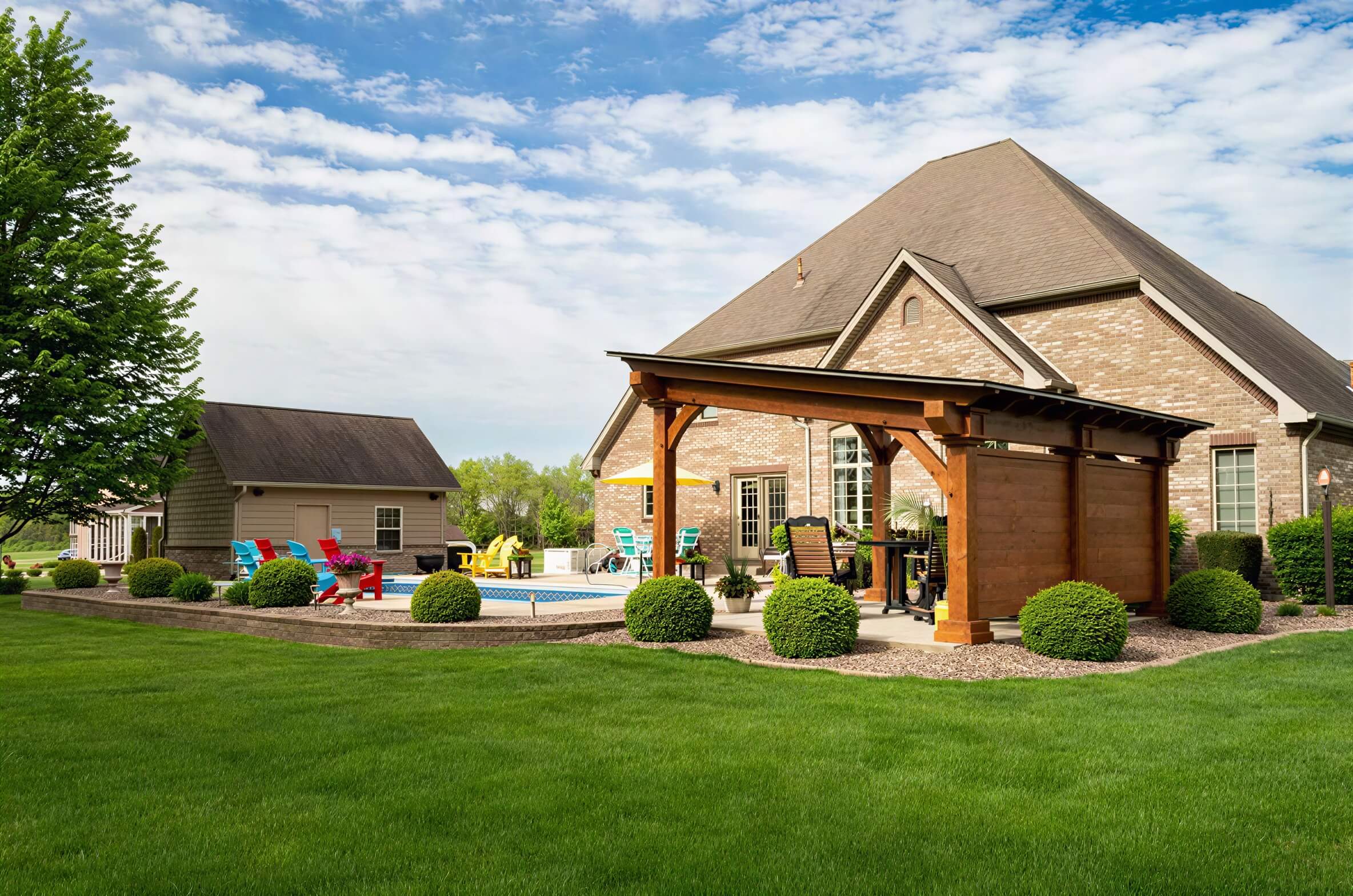 A spacious lawn with a Brookside Timber Frame Glazier Hideaway Pavilion provides a shaded retreat