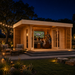 Asta 70 wooden garden room illuminated on a clear summer night, with family and friends cheering together while watching a live football game inside.