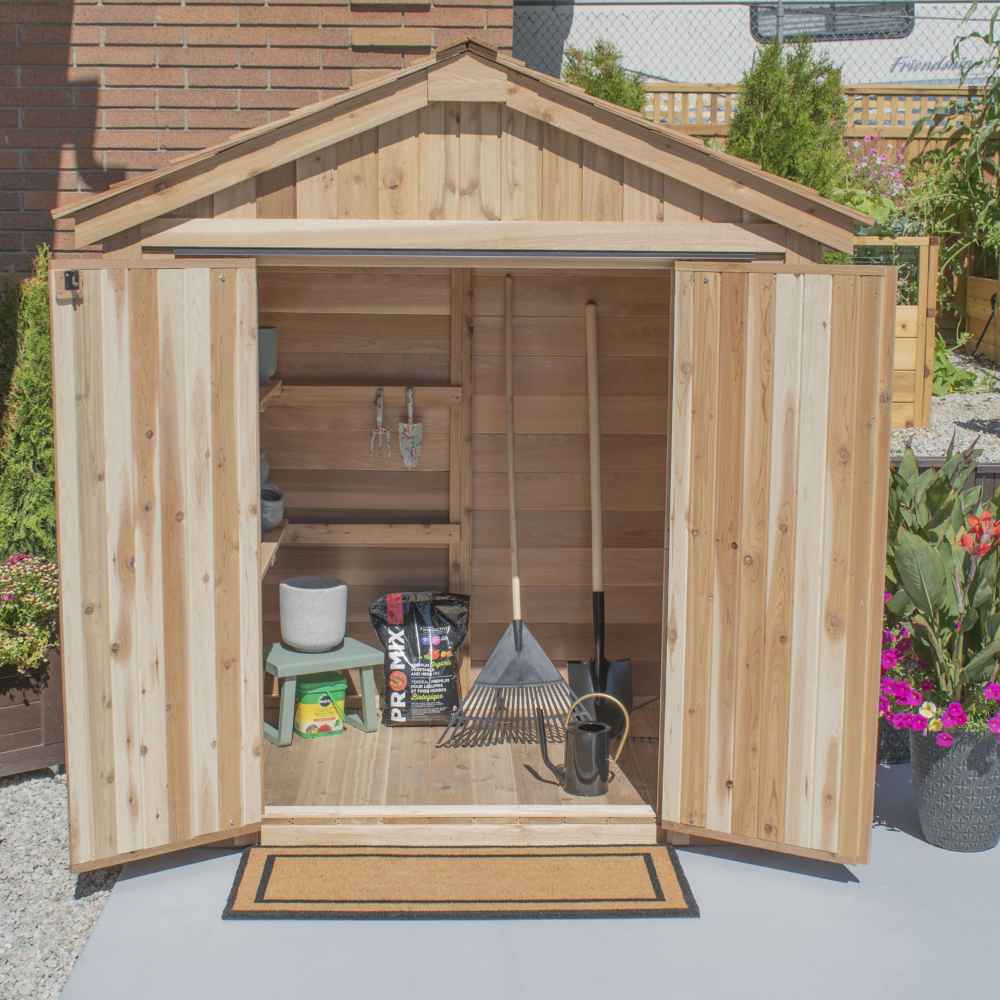 A straight-on view of the open Outdoor Living Today SpaceMaster 6×4 with Double Door reveals gardening supplies and tools organized inside the shed with plants outside