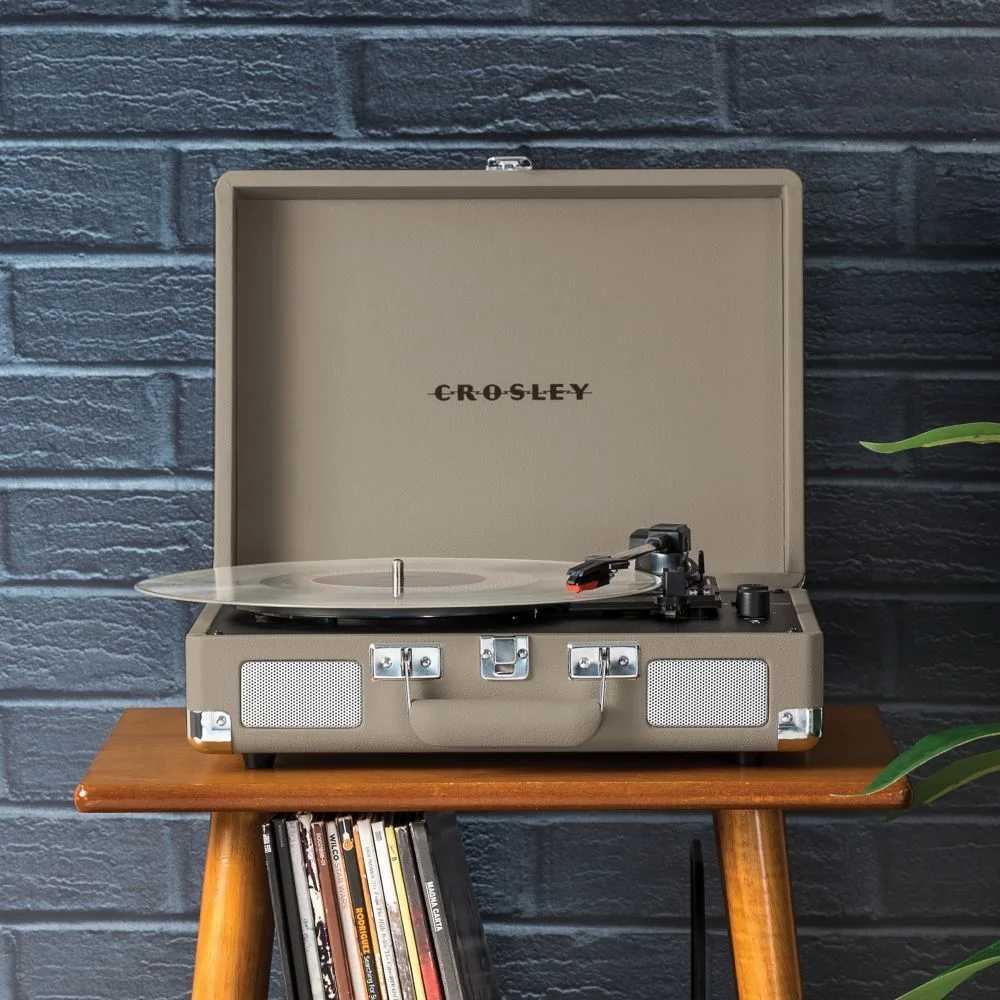 A stylish Crosley Cruiser Plus Portable Turntable with Bluetooth InOut - Taupe sits open on a wooden table