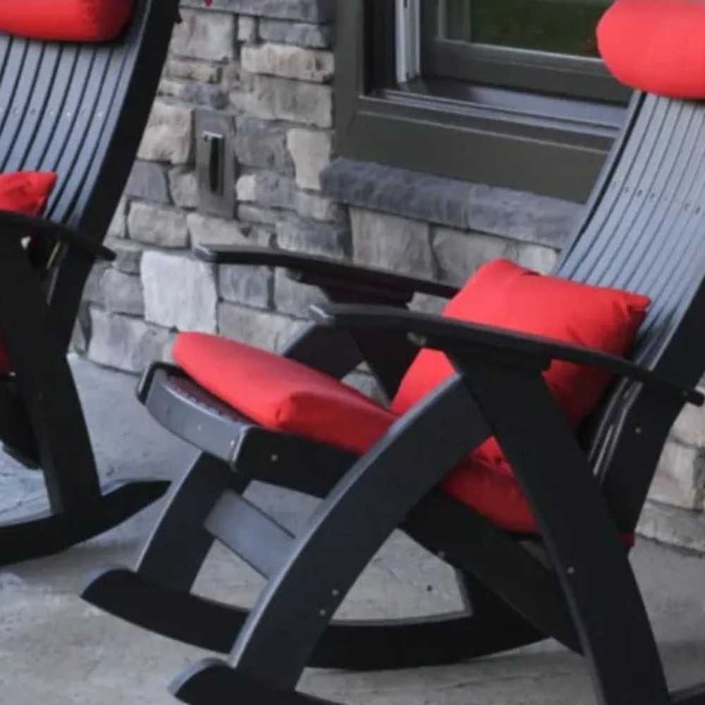 A stylish black rocking chair on a stone patio is enhanced by a bold red LuxCraft Lumbar Pillow