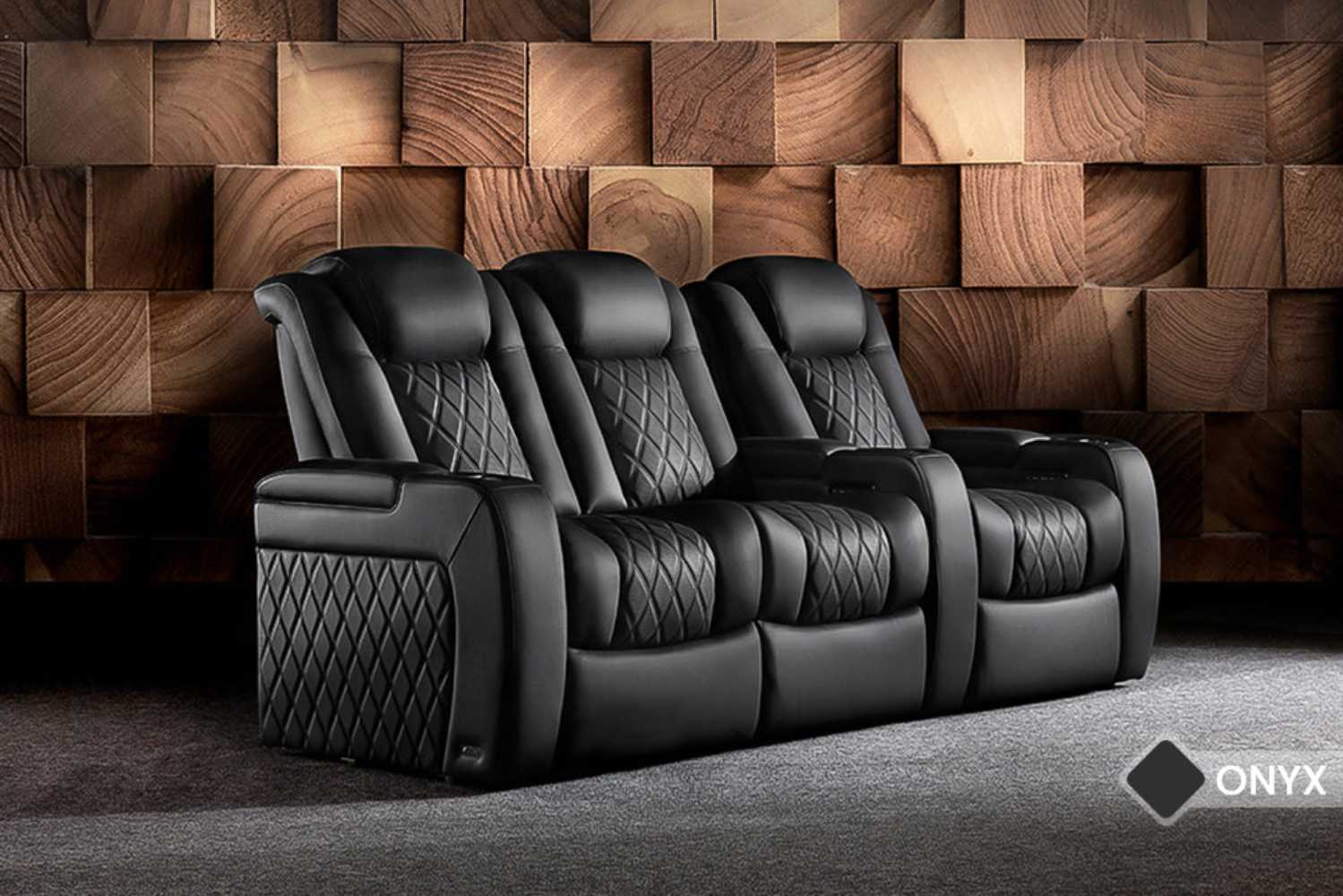 A stylish set of three onyx Valencia Tuscany Luxury Edition Home Theater Seating recliners with quilted leather and luxurious finishes sits against a textured wood wall