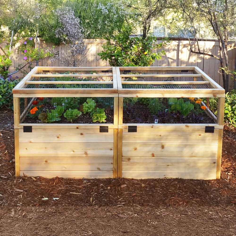 A sunny backyard features a see-through mesh-topped Outdoor Living Today 6×3 Raised Garden Bed brimming with vegetables and flowers