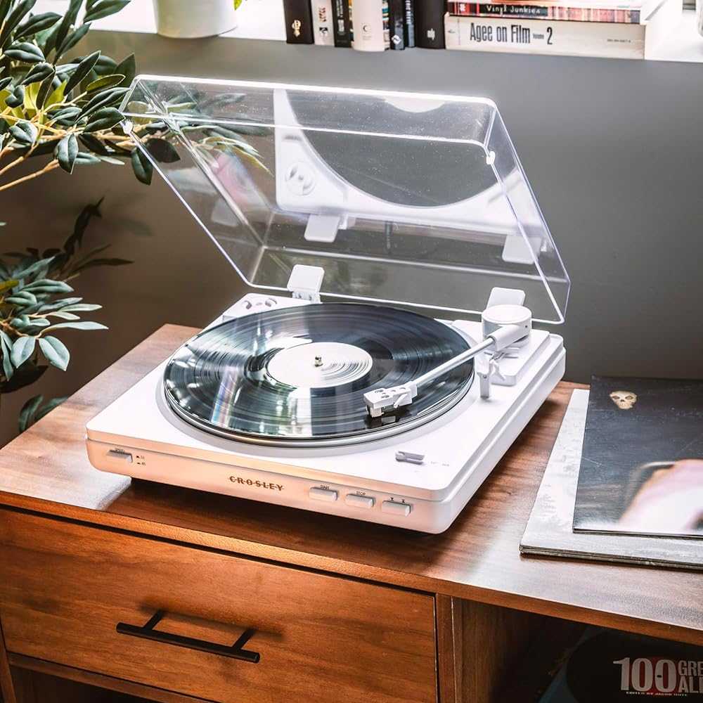 A vinyl record spins on the Crosley T400D Component Bluetooth Turntable - White with its transparent dust cover open on a wooden surface