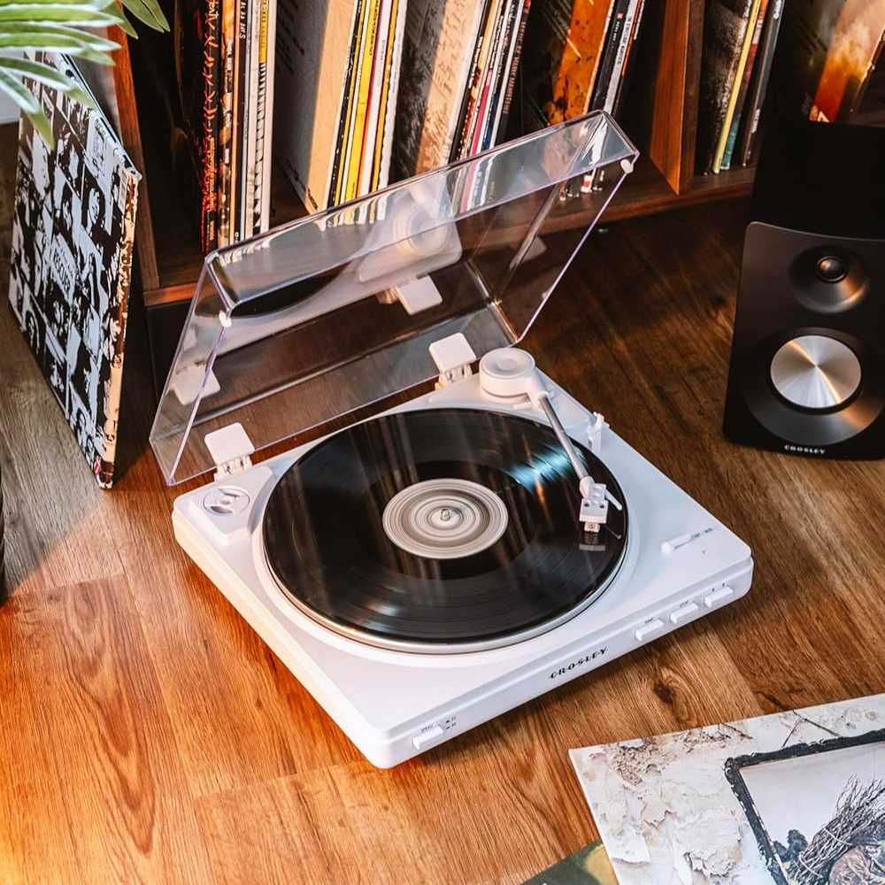 A vinyl spins on the Crosley T400D Component Bluetooth Turntable - White, surrounded by a collection of vinyl albums stored neatly on a shelf