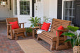 A warm brown glider set with bright red LuxCraft 15 Toss Pillows on a brick porch surrounded by plants