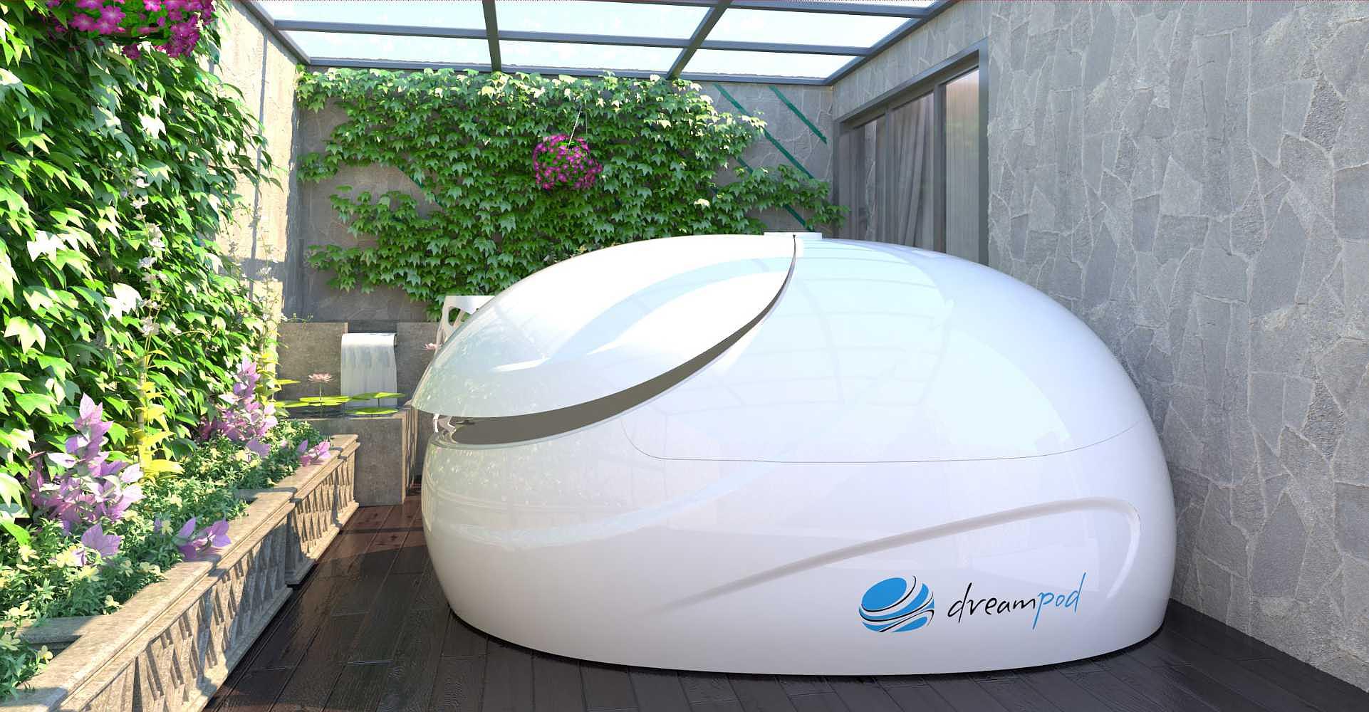 A white Dreampod Sport Float Pod is placed in a green outdoor patio with a lush vertical garden on the wall beside it