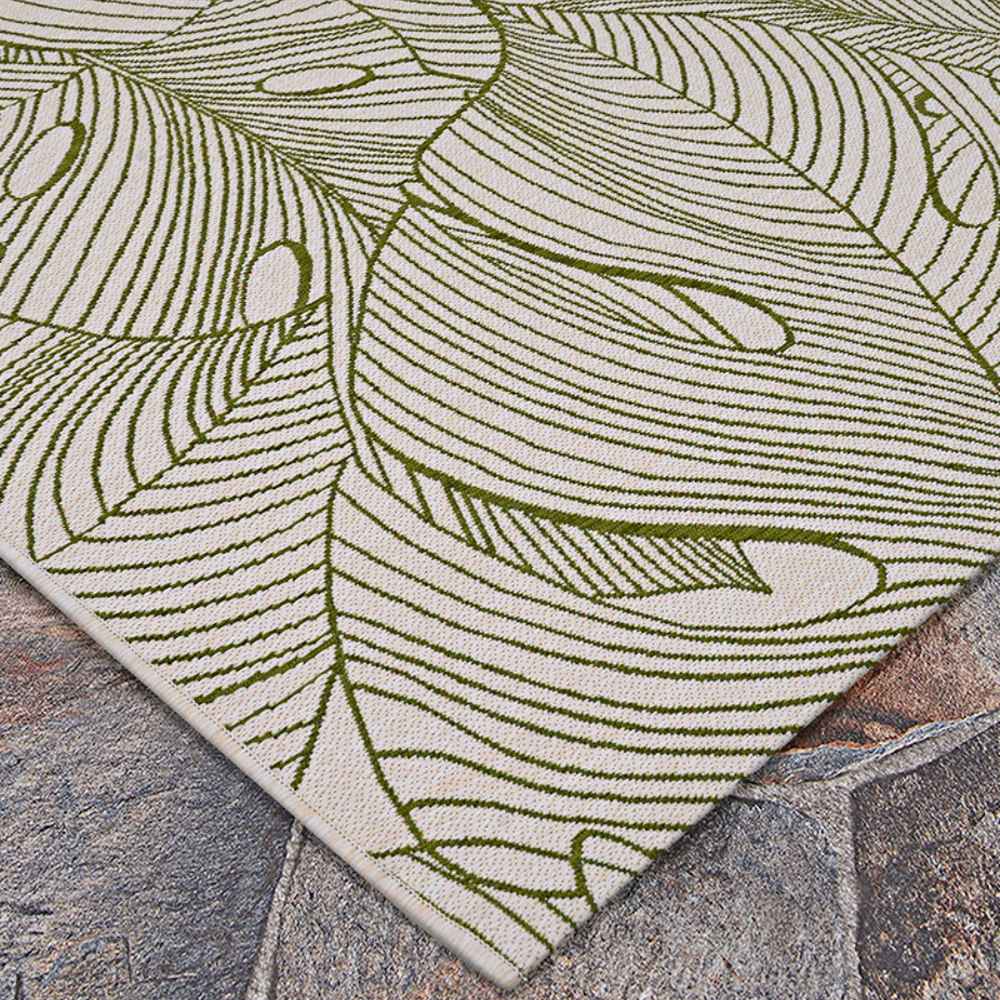 A wide-angle view of the Couristan Castille Indoor/Outdoor Rug - Palma/Fern displays its bold green leaf design sprawling across a white background