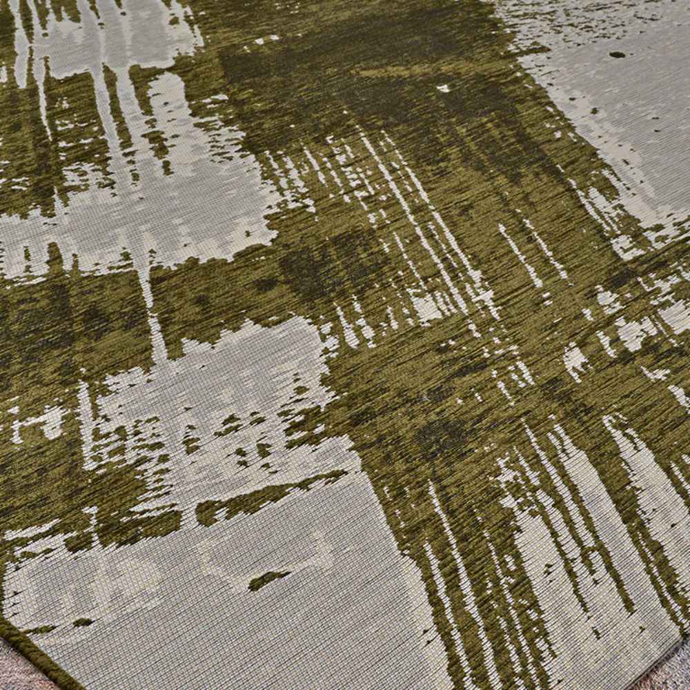 A wide shot of the Couristan Castille Indoor/Outdoor Rug - Canvas/Tea Leaf highlights its contemporary abstract brush marks in green across a neutral base