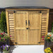A wooden double-door shed with black metal roof sits surrounded by colorful planters, showcasing the Outdoor Living Today Grand Garden Chalet
